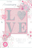 The image shows a refined anniversary card that captures the soft, enduring romance of a couple sharing life together in Abbey Wood. At its heart, the word LOVE appears in raised, softly shimmering glitter, each letter neatly formed and outlined with a delicate silver sheen. The O is transformed into a subtly sparkling heart, textured to appear slightly more pronounced, as though inviting touch. This central motif rests on a backdrop of powdery blush pink, providing a warm, gentle glow reminiscent of evening light over the local gardens and quiet residential streets. Around the word, a constellation of hand-drawn flowers unfolds in pale blush, muted mauve, and hints of ivory and silvery grey. Their petals are rendered with a watercolor softness, fading gently at the edges as if brushed onto the card by hand. Slim vines, swirls, and tiny butterflies thread between the blooms, adding a sense of quiet movement akin to a breeze stirring blossoms in a sheltered Abbey Wood garden. Above and below the main motif, elegant script spells out tender anniversary sentiments, including phrases in the spirit of On Our Anniversary and I love you today and always. The lettering is graceful and understated, allowing the floral artwork and glittered heart to remain the star. The whole composition feels calm, intimate, and thoughtfully arranged, much like a bespoke anniversary bouquet crafted for local delivery-a paper expression of shared memories and gentle devotion, perfect for marking another year together in the Abbey Wood community.